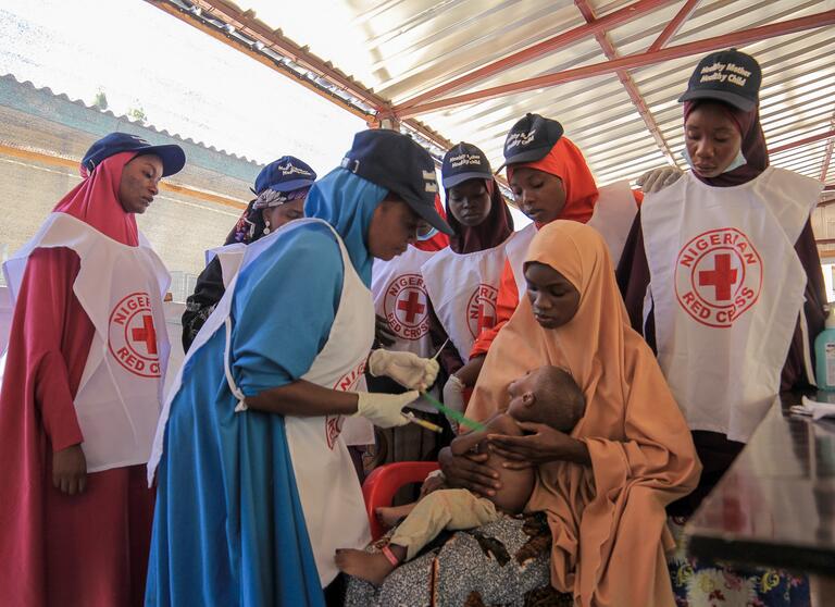 Nigerian 澳洲幸运10官网平台 volunteers provide care to a child suffering from acute malnutrition.